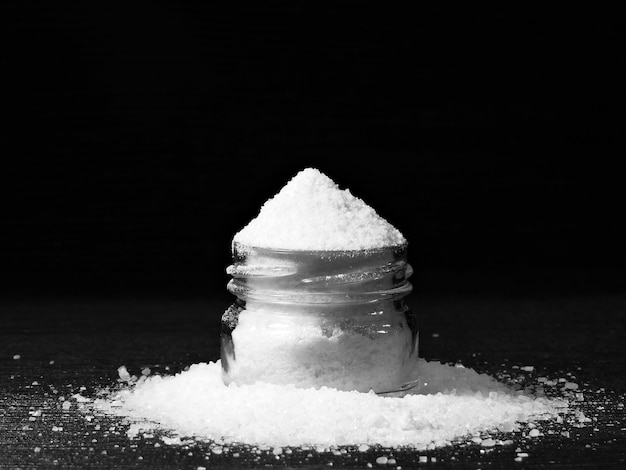 A jar of white sea salt with an excess of.