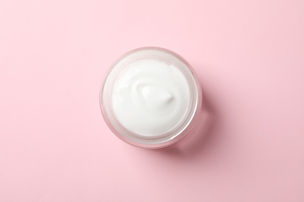 Jar of winter cream for skin on pink background, space for text.