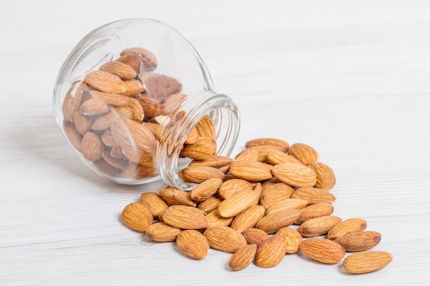 Jar with  almonds on white wood background