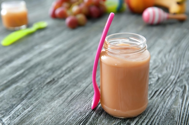 Jar with baby food on wooden table