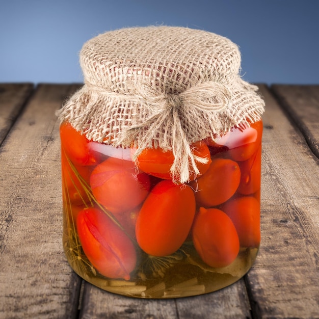 Jar with canned tomatoes on background