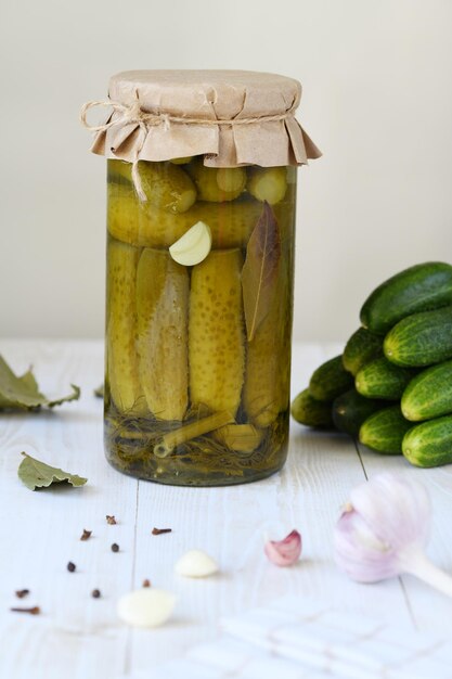 A jar with cucumbers prepared for pickling and ingredients for the marinade garlic dill horseradish leaves currant leaves against the background of a box with readymade canned cucumbers