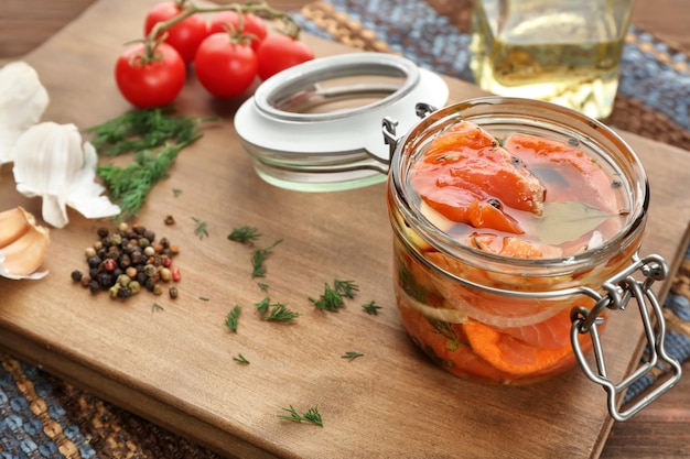 Jar with delicious marinated salmon on table