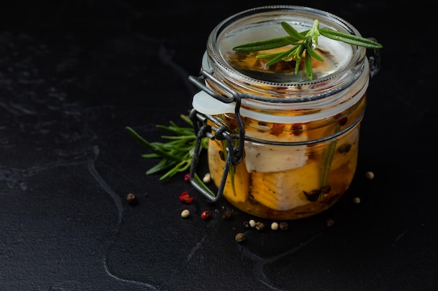 The jar with feta cheese and spices on a dark background