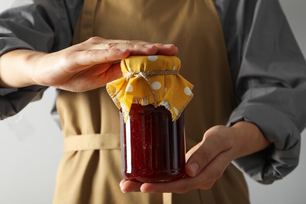 Jar with fig jam in hands on white background