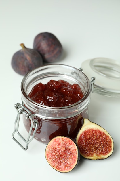 Jar with fig jam and ingredients on white background