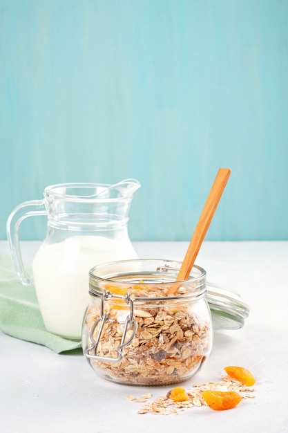 Photo jar with homemade granola or oatmeal muesli with nuts and dried fruits and milk.