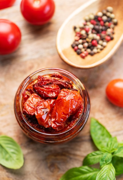 Jar with homemade sun dried tomatoes with fresh herbs and spices