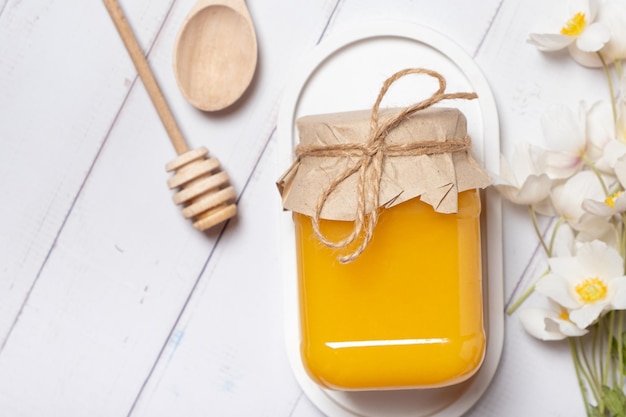 Jar with honey and flowers on wooden background top view flat lay