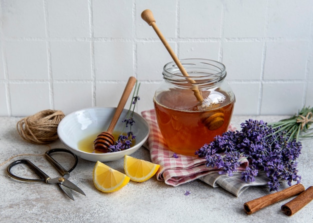 Vaso con miele e fiori di lavanda fresca su fondo di cemento