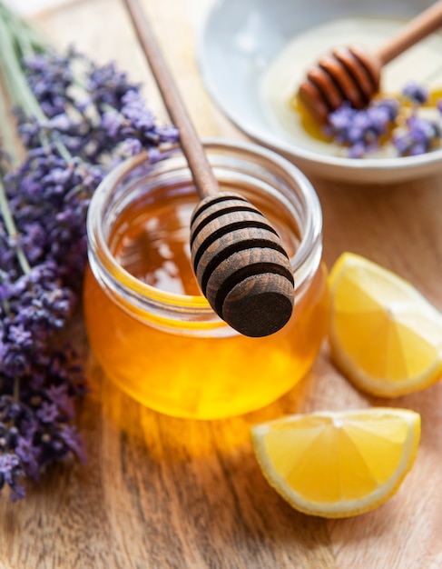 Jar with honey and fresh lavender flowers on a wooden background