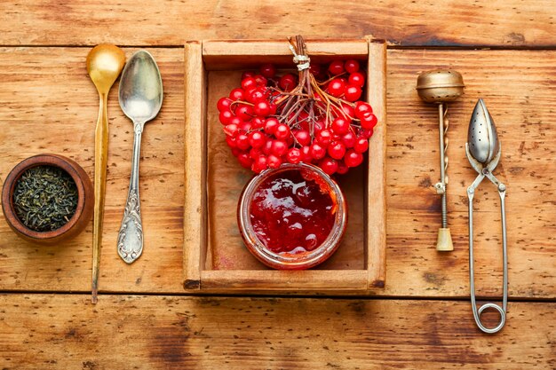 Foto vaso con marmellata e bacche di viburno. deliziosa marmellata fatta in casa su una tavola in legno rustico