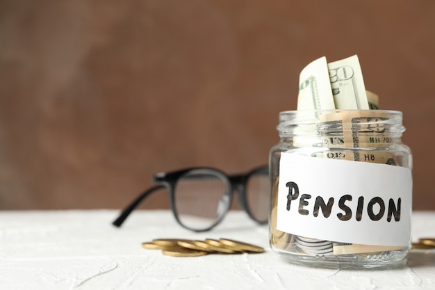 Jar with money and inscription Pension against brown surface