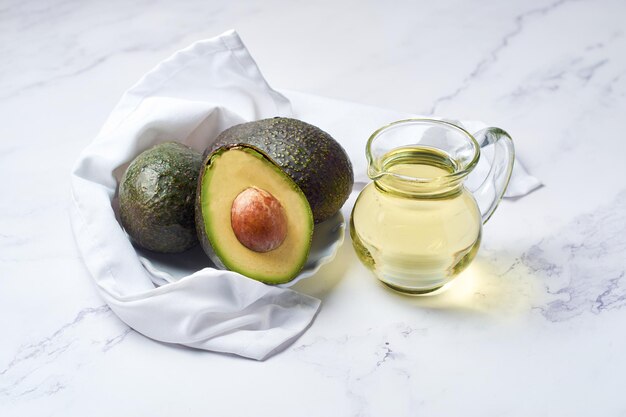 Jar with oil and ripe fresh avocado on table