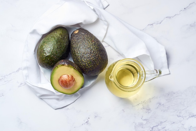 Jar with oil and ripe fresh avocado on table