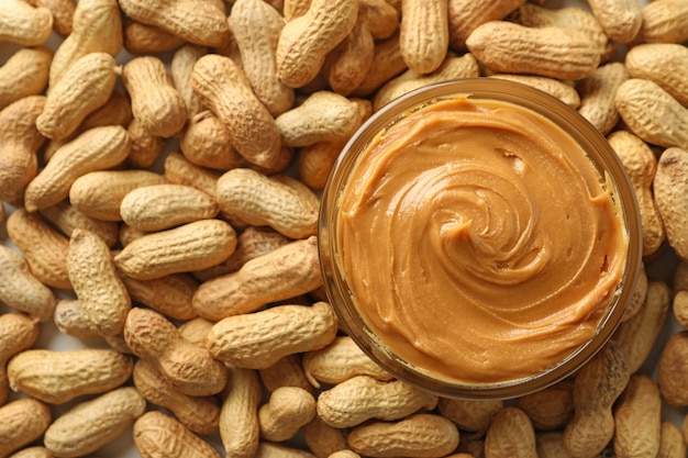 Jar with peanut butter on peanut background close up