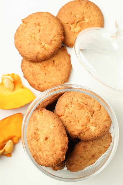 Jar with pumpkin cookies on white background.