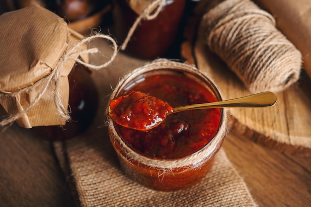 Jar with a spoon and plum jam with craft decor