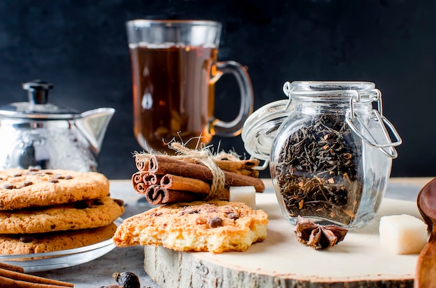 お茶、自家製クッキー、暗い背景にお茶のスパイスの瓶、