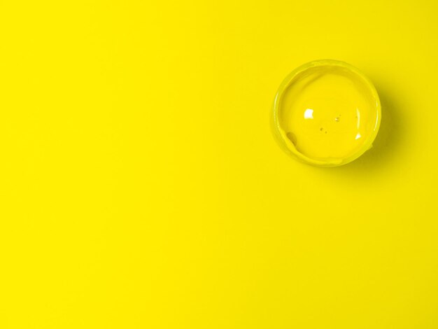 A jar of yellow paint on a yellow background Bank of gouache Bright background Artist's workshop