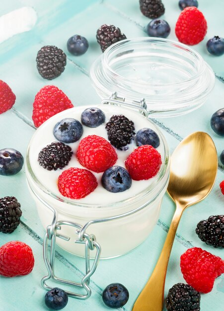 Jar of yogurt with blueberries, blackberries and raspberries.