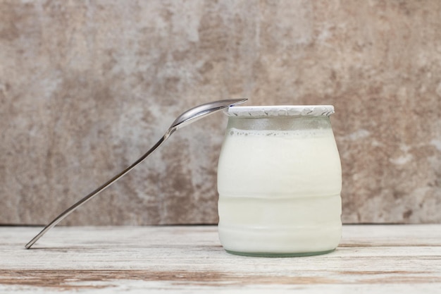 Photo a jar of yogurt on a wooden background