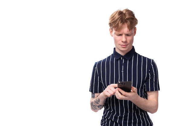 jarige blonde man in een gestreepte polo aan het chatten op een smartphone