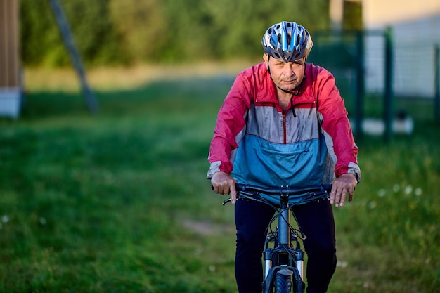 jarige man fietst met een fietshelm op het platteland met een ernstig gezicht