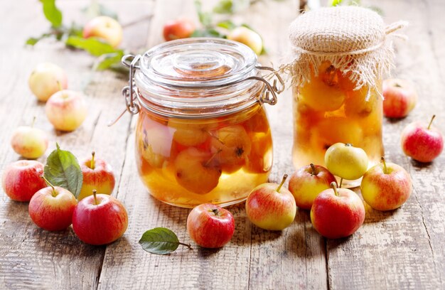 Jars of apple jam with fresh fruits on wooden table