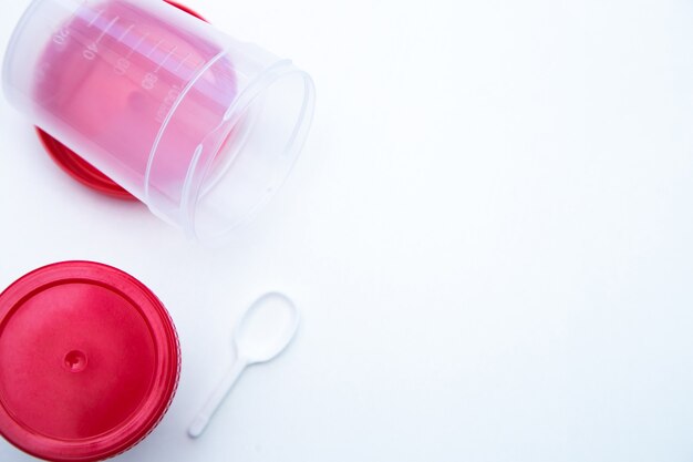 Jars for collecting tests with a red lid and a spoon on a white background  high quality photo