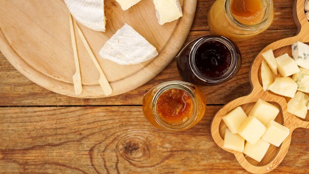 Jars of homemade jams and honey cheeses on a wooden table Cheese plate