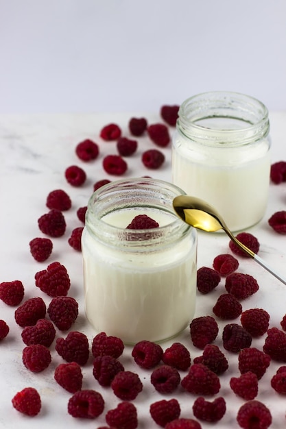 Jars of homemade yogurt surrounded by raspberries Healthy eating