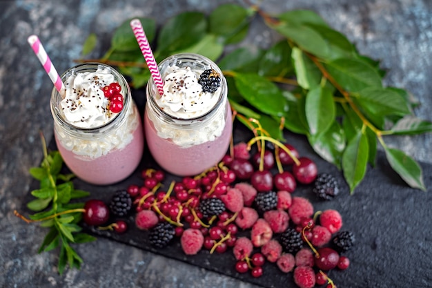 Jars of milkshake with cranberries, strawberries and blueberries