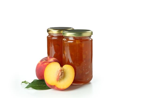 Jars of peach jam and ingredient isolated on white background