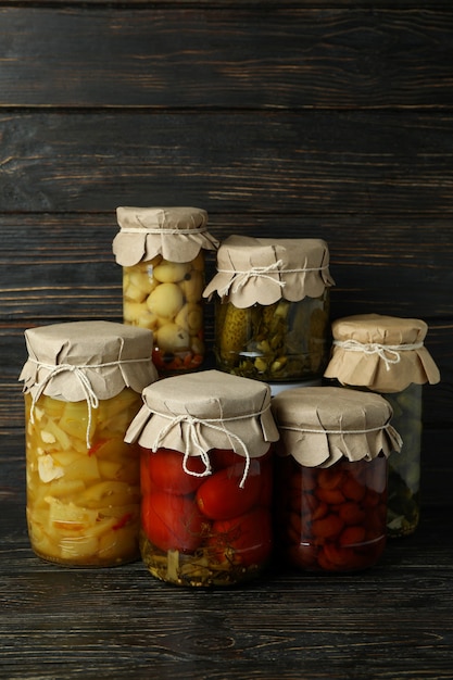 Jars of pickled vegetables on rustic wooden background