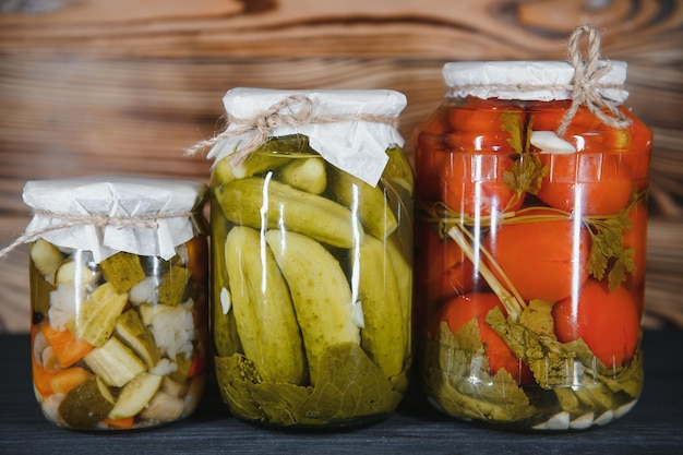 Jars of pickled vegetables on rustic wooden background