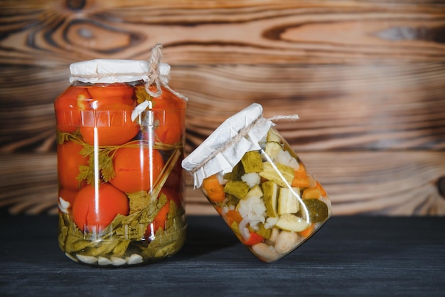 Jars of pickled vegetables on rustic wooden background