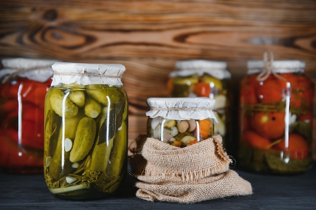 Jars of pickled vegetables on rustic wooden background