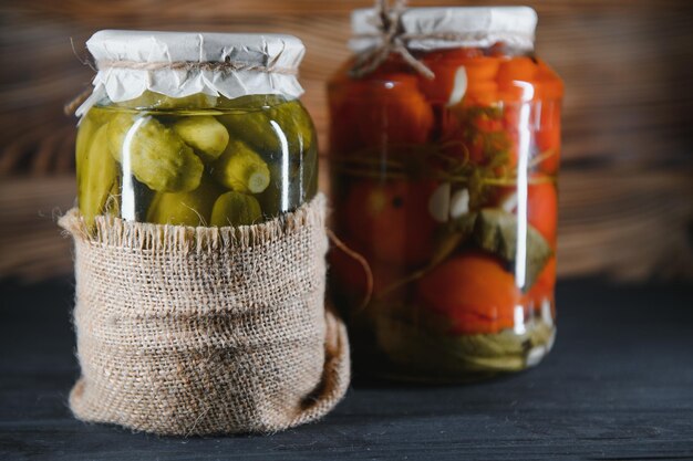 Jars of pickled vegetables on rustic wooden background