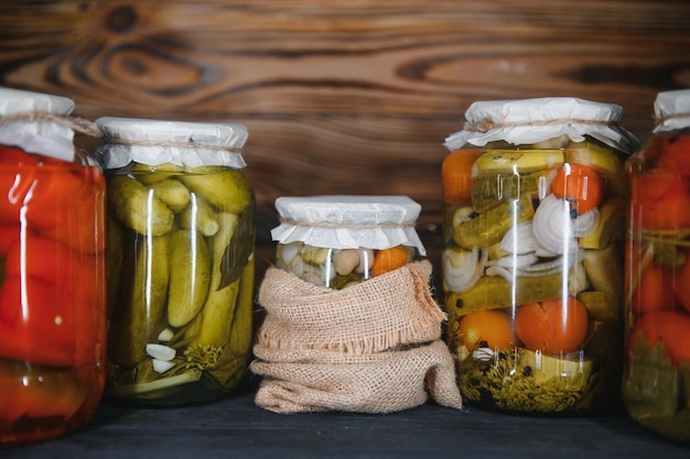 Jars of pickled vegetables on rustic wooden background