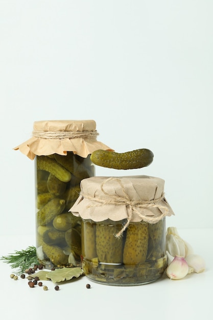 Jars of pickles and ingredients on white background