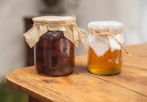 Jars of strawberry jam and honey on a wooden table