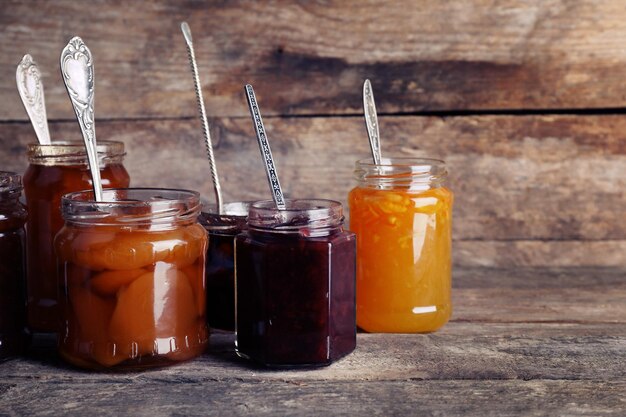 Jars of tasty jam on wooden background