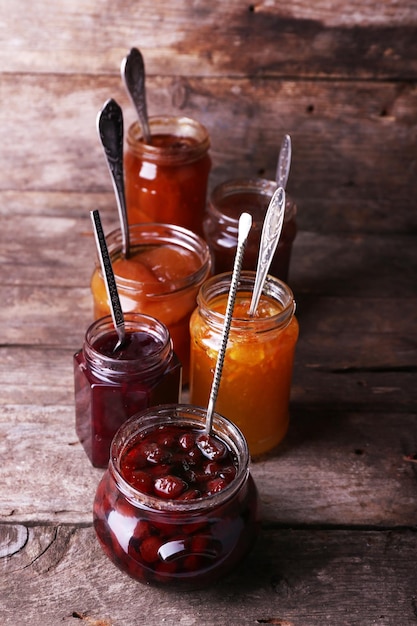 Jars of tasty jam on wooden background