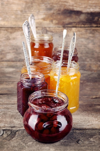 Jars of tasty jam on wooden background