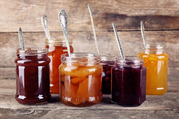 Jars of tasty jam on wooden background