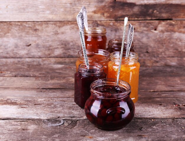 Jars of tasty jam on wooden background