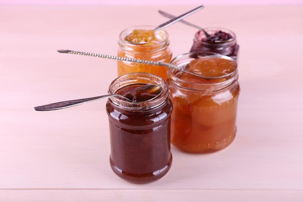 Jars of tasty jam on wooden background