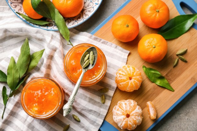 Jars of tasty tangerine jam on grey table