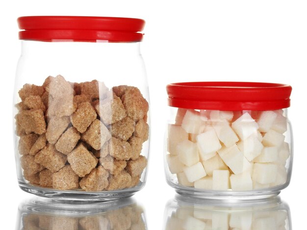 Jars with brown cane sugar lump and white lump sugar isolated on white